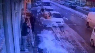 Gaziantep’te bir iş yerinin önünde bekleyen çalışan, çatıda biriken kar