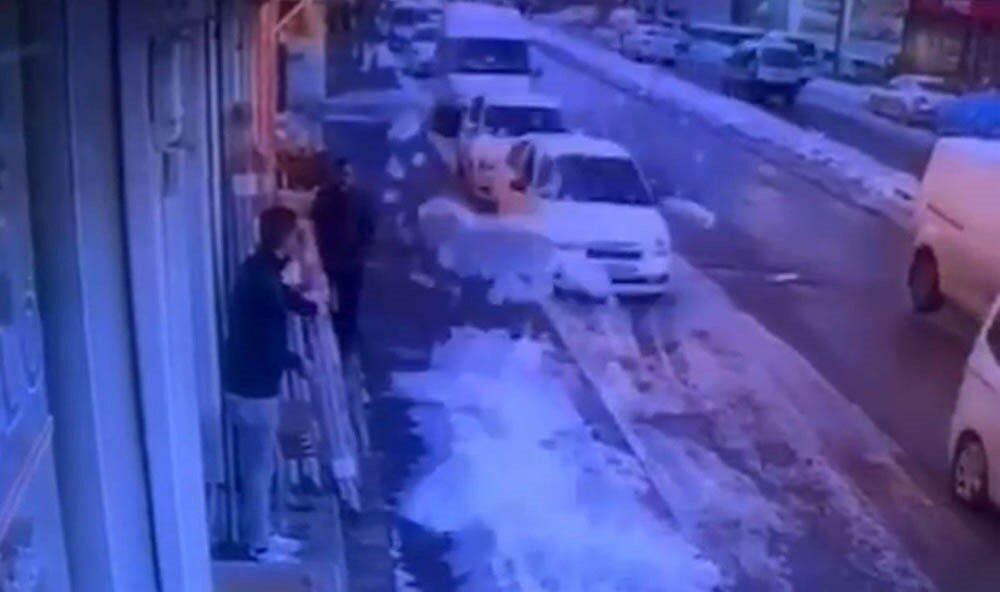 Gaziantep’te bir iş yerinin önünde bekleyen çalışan, çatıda biriken kar