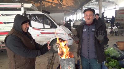 Kütahya’da soğuklardan etkilenen pazarcı esnafı, tezgahlarının yanına koydukları tenekede ateş