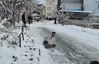 Tokat’ın Niksar ilçesinde karlı ve kaygan yolda poşetlerle kayan gençler,