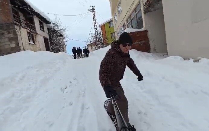 Tokat’ın Başçiftlik ilçesinde kar yağışının ardından snowboardla sokağa çıkan dayı-yeğen,