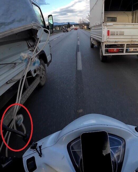 Antalya’da iki kamyonet arasından geçmeye çalışan motokurye, sarkan branda ipine