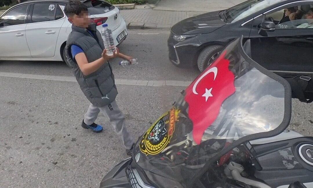 Eskişehir’de trafik ışığının altında su satan çocuk, bir motosikletliye camında